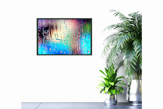 close up of rain on window with blue, green, pink, and yellow lights behind picture on wall