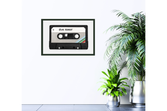 old cassette tape with "Our Songs" written on it, gray background print hanging on wall