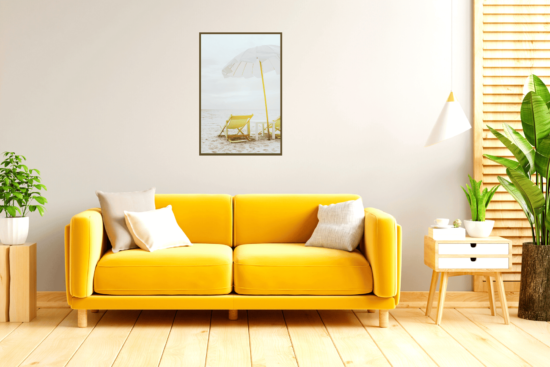 Yellow beach chairs with white umbrella on beach wall print above yellow sofa in living room