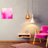 Pink abstract art print on wall beside pink chair and gold light
