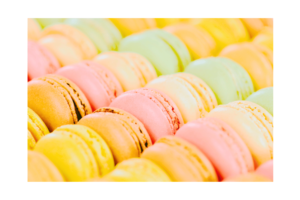 close up of macaroons in shades of yellow, pink, and green wall print